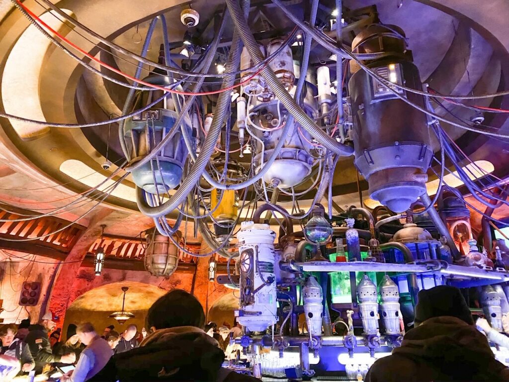 lots of wires and tubes above space themed bar and colorful lights