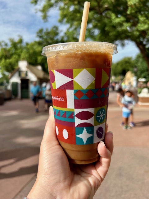 hand holding iced coffee in a decorative colorful cup from Joffrey's magic kingdom breakfast