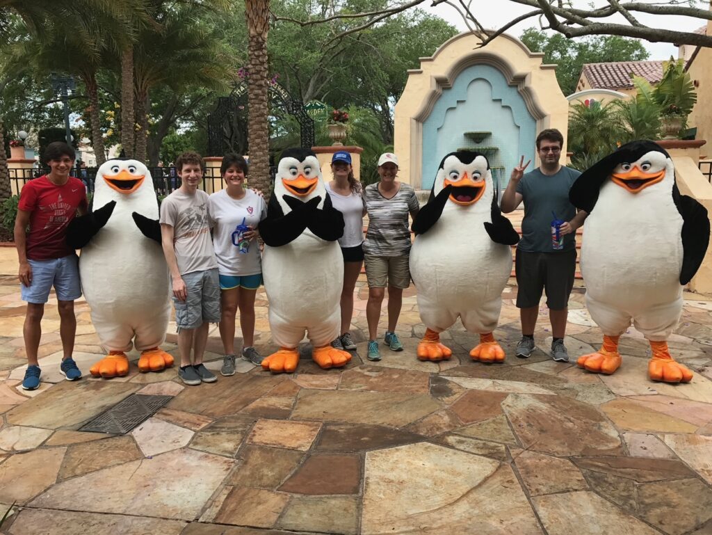 This photo shows a happy family taking photos with the penguins from Madagascar. because they knew what mistakes to avoid at Universal Orlando, so they got to do meet and greets!