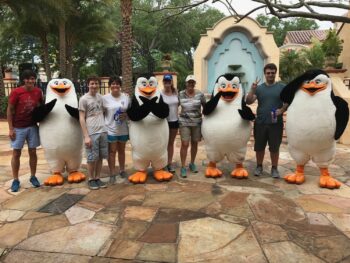 A family stands with the penguins of Madagascar during a meet and greet because they knew which mistakes to avoid in Universal Studios Orlando and were able to schedule in all attractions!