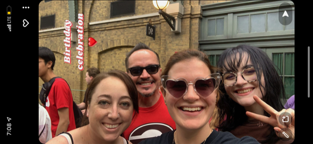 A selfie of four guests in front of the platform of 9 3/4 prepares them for the park to park hop on the Hogwarts Express.