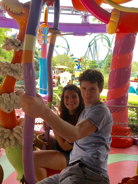 Two people sit on a Suess-Landing ride: you can see the curves of the park behind them, which is one of the Universal Orlando secrets: there are no straight lines in Suess-landing! 