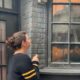 A girl stands in front of a window in Diagon Alley with her interactive wand, looking for one of the Universal Orlando secrets: a special interaction spot not located on a map!