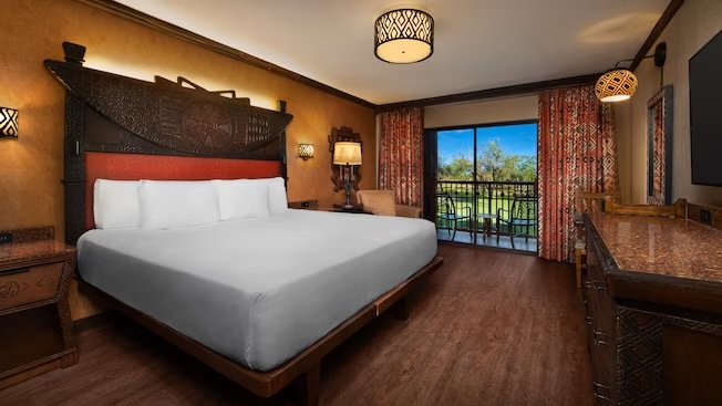 bed in dark and wooden decorated room with trees outside the window at animal kingdom lodge best themed rooms