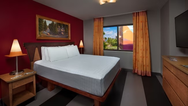 bed in hotel room with dark red walls and orange curtains art of animation cars room best themed rooms