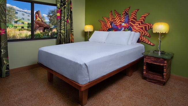bed with colorful headboard, green wall, and brown carpet with lion statue in the window best themed rooms