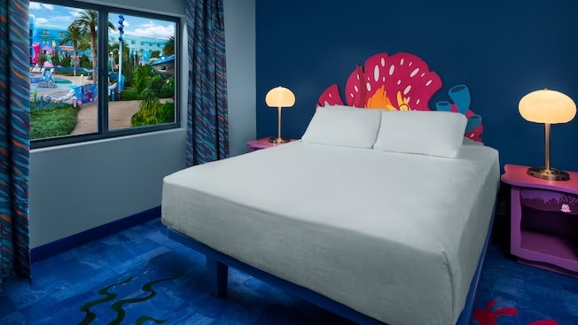 bed with pink coral headboard and blue ocean looking carpet and ocean creatures statues outside the window 