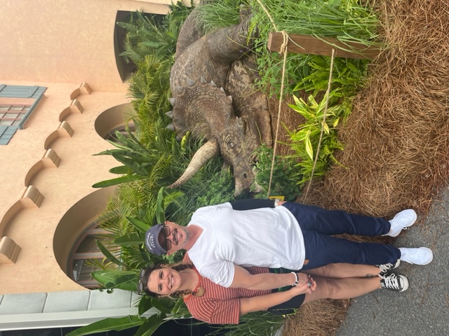 A couple stands in front of the Dino exhibit at a tribute store, whose free access helps save money at Universal Orlando.