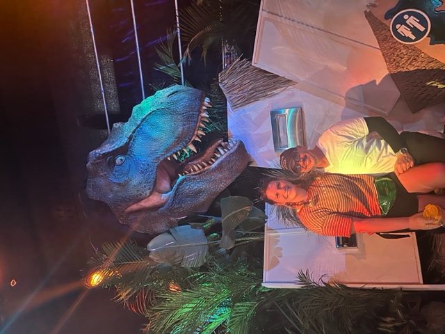 A couple sits on one of the prop designs of the Jurassic Park Tribute Store, and the woman holds a freestyle cup, which is a savior at the parks. 