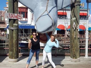 A girl and her friend pose at the jaws shark after asking someone to take a photo for them: this helped them save money at Universal Orlando because they opted out of the expensive photo pass.