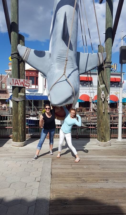 A girl and her friend pose at the jaws shark after asking someone to take a photo for them: this helped them save money at Universal Orlando because they opted out of the expensive photo pass.