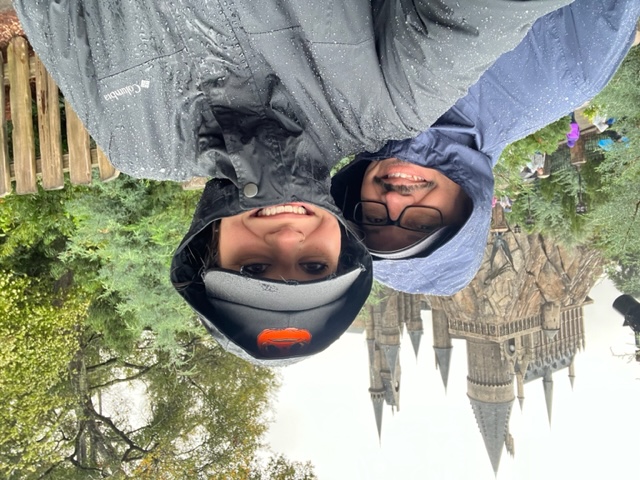 A couple stands in front of Hogwarts inn rain coats, enjoying the rainy day and comfortable because of this smart purchase! 