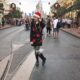 woman in Santa hat, holiday sweater and leggings and boots in front of castle in disney what to wear in disney in winter