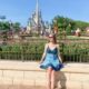 woman in blue dress sitting in front of cinderella castle what to wear in disney in spring