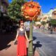 woman in red skirt and black polka dot top near orange Mickey Mouse pumpkin decoration