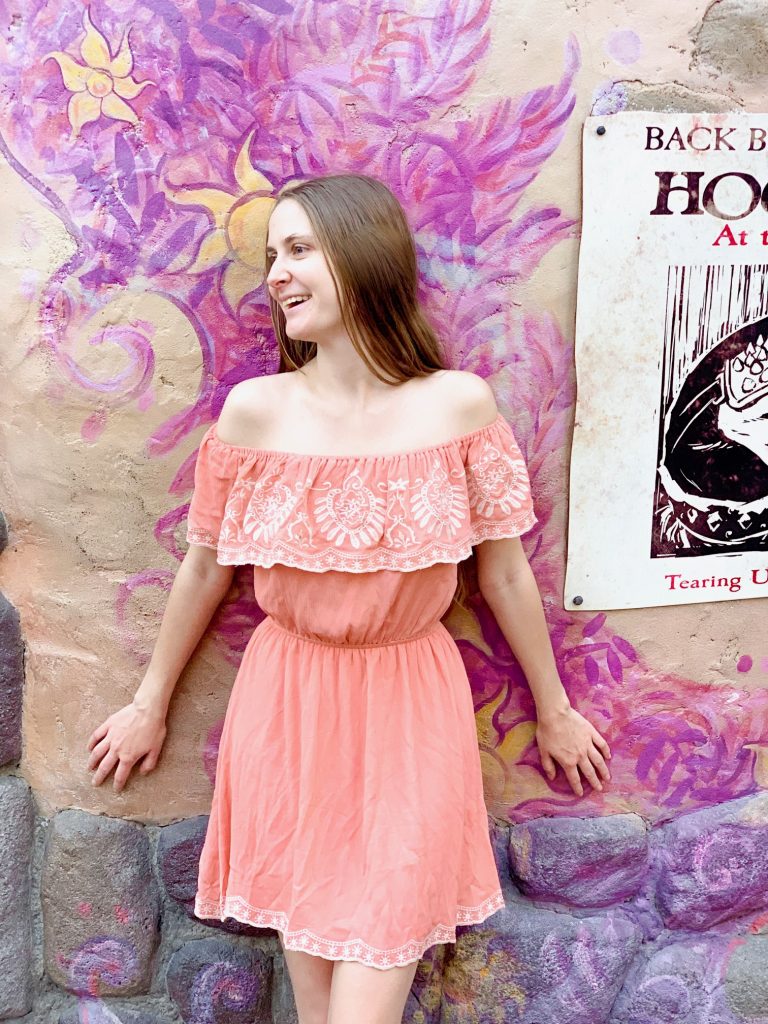 woman in peach dress in front of purple painted wall 