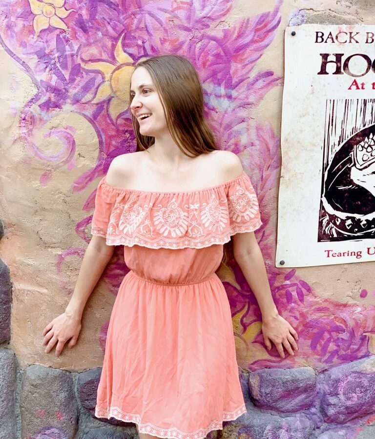 woman in peach dress against colorful purple painted wall