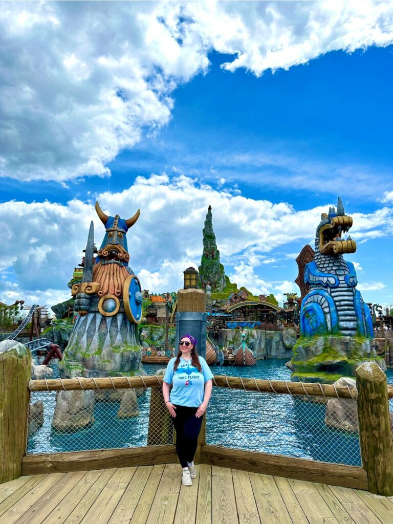 A girl in leggings and a blue shirt stands in front of the Isle of Berk, knowing that her outfit is perfect for her Epic Universe packing list.