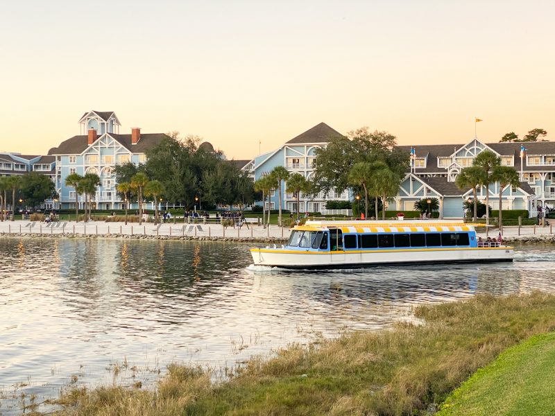 A ferry boat travels on the lake by a Disney resort at sunset. 