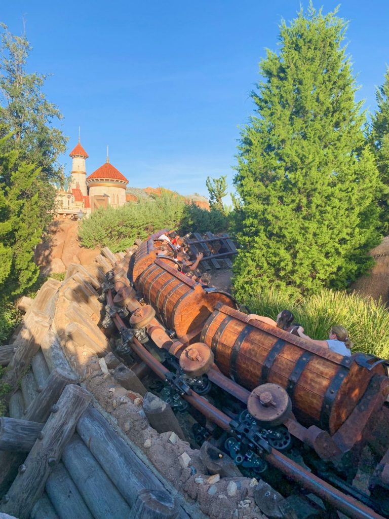 The Snow White mine train hurdles around a corner, the train swinging and guests laughing. 