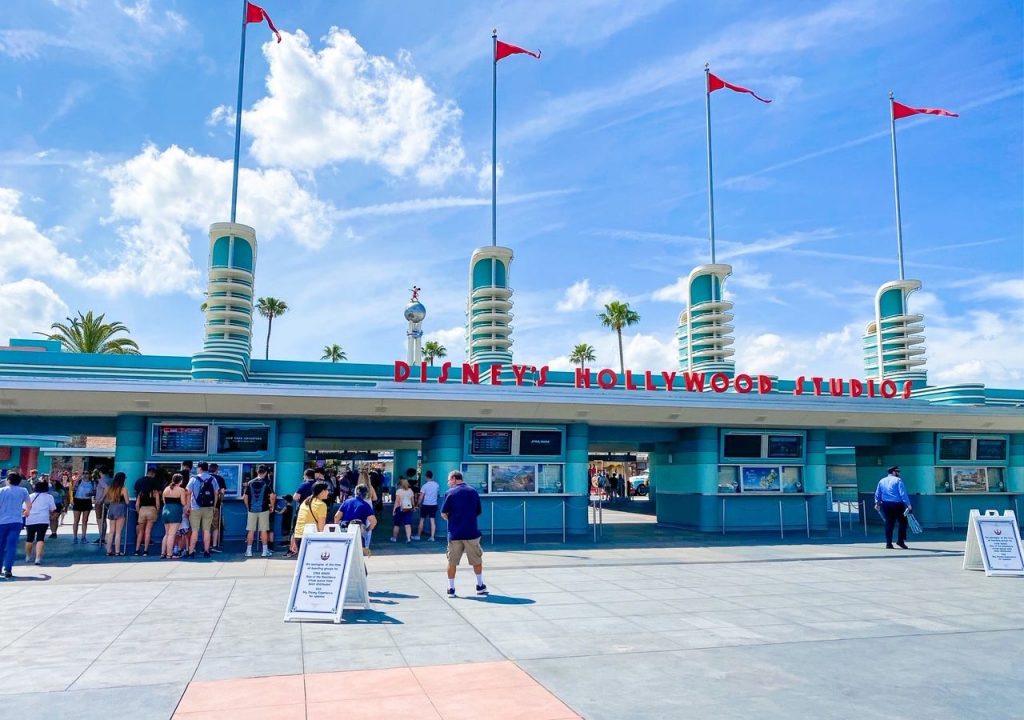 The entrance of Hollywood Studios shows a vibrant 50's theme with blue buildings, red lettering and red flags. 