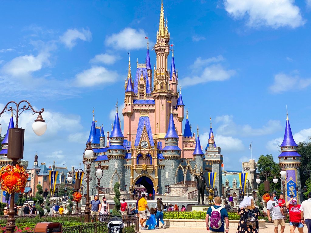 pink and blue fairytale castle with people in front of it with a blue sky behind it