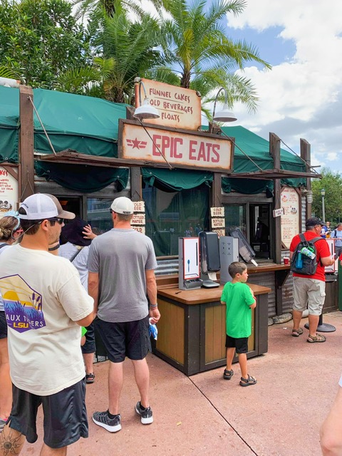people in line at food booth with wooden sign