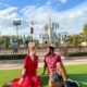 man and woman sitting on grass facing each other in front of fairytale castle disney world picnic spots