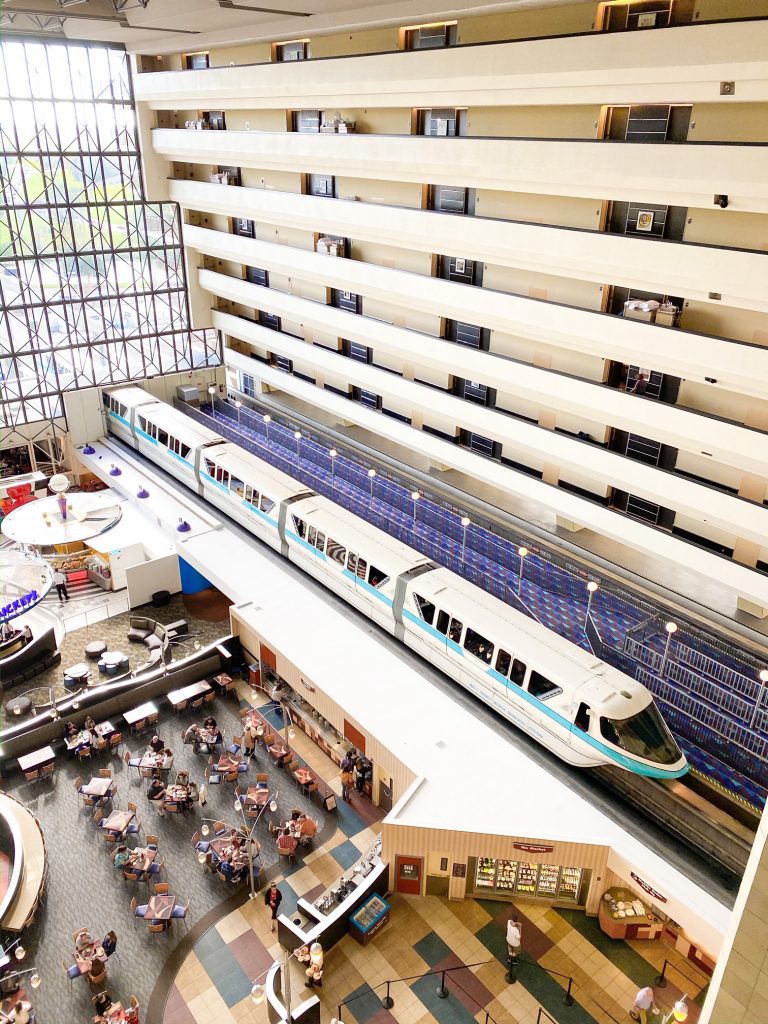 white monorail vehicles going through hotel with rooms and people in view 2 days at disney hotel choice 