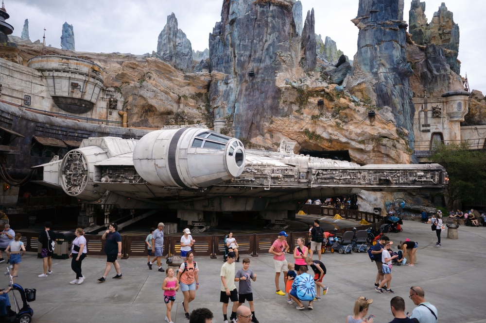 large grey spaceship (millennium falcon) with people in front of it and rock mountains behind it disney rides not worth the wait